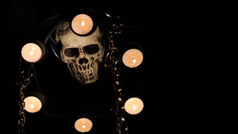 dummy human skull surrounded by candles on chains