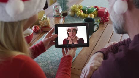 Pareja-Caucásica-Con-Sombreros-De-Santa-Usando-Tableta-Para-Videollamada-Navideña-Con-Mujer-En-Pantalla