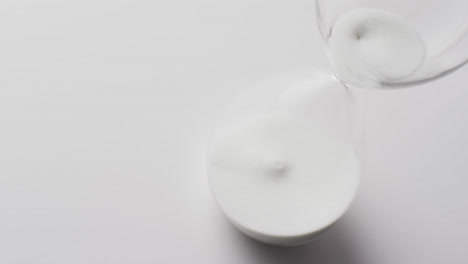 video of hourglass with sand pouring, copy space on white background