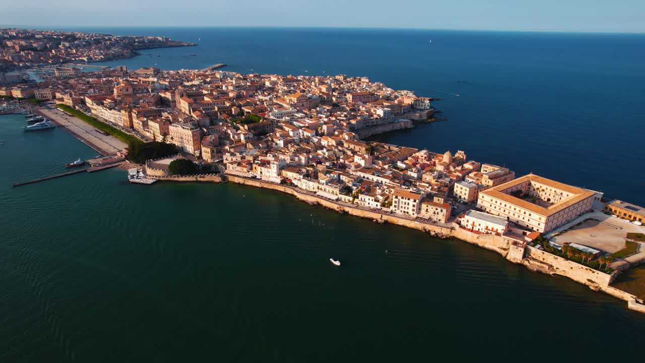 Sunset aerial of Ortigia island in Syracuse, Sicily, with historic rooftops and coastline architecture