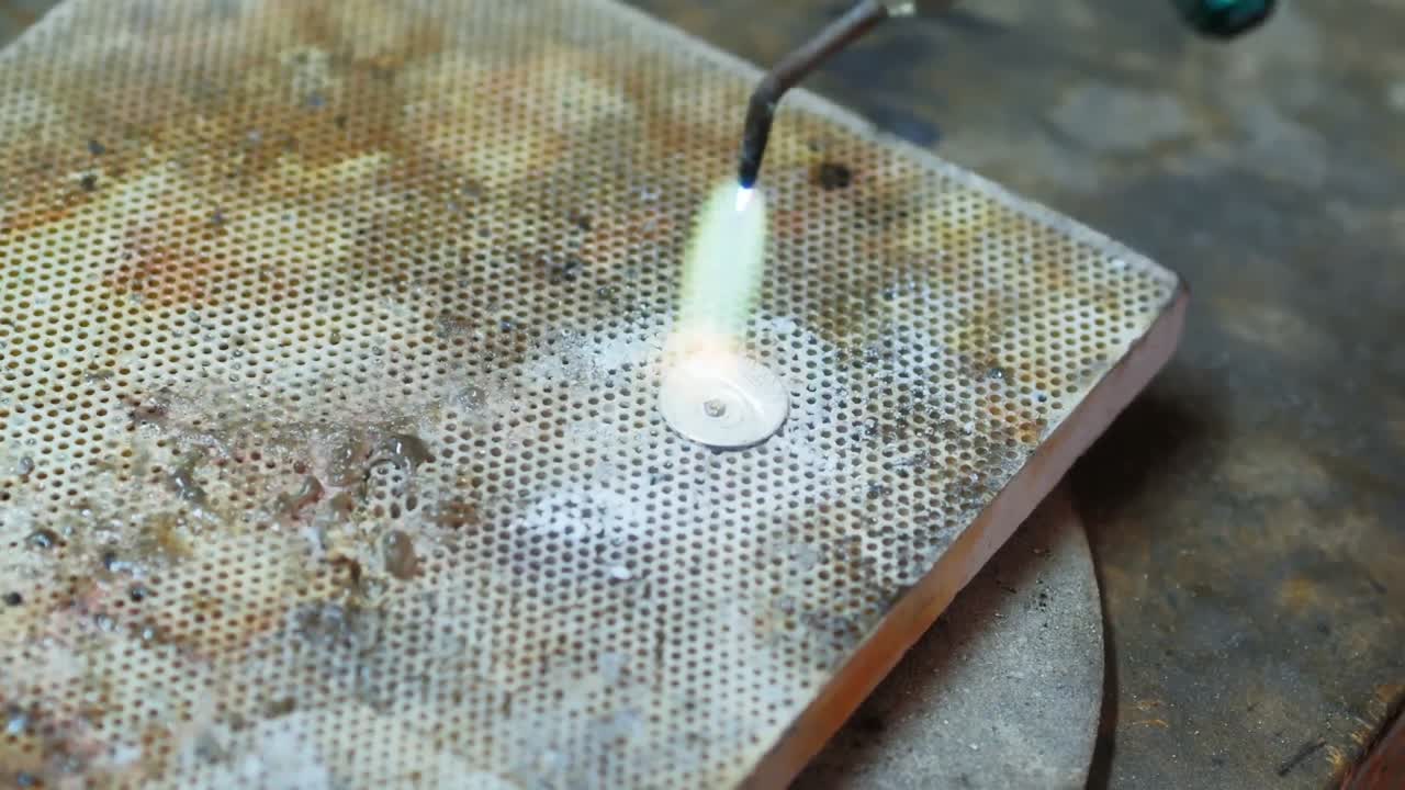 Close-up of Craftswoman blowing a torch to melt metal
