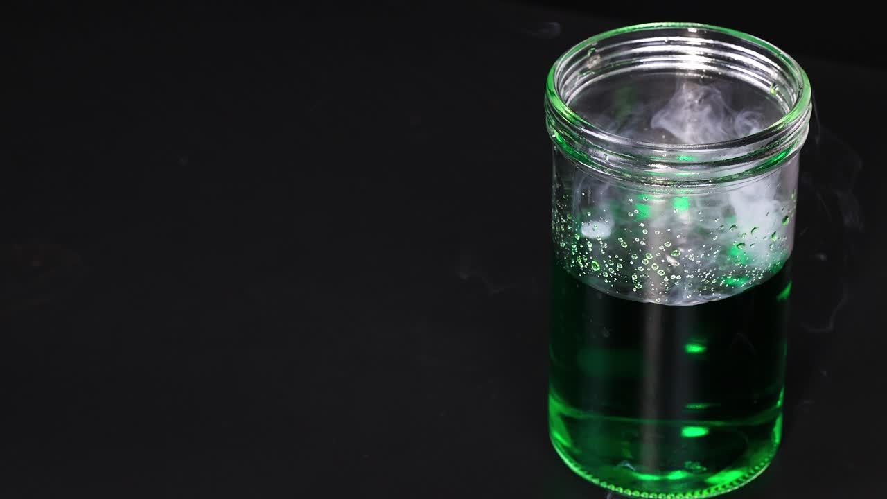 녹색 액체가 들어있는 컵은 건조한 얼음과 반응하여 통제된 환경에서 거품과 증기 효과를 발생시니다.