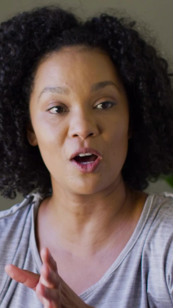 Vertical video: Responding to offcamera cue woman speaking at home in gray tee and square watch