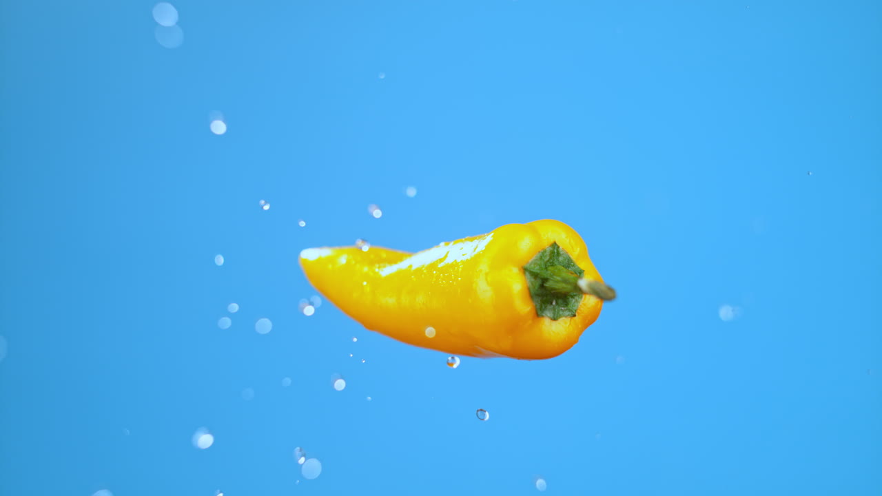 solo pimienta amarilla chile saltando en el aire y volando con gotas de agua, verdura para cocinar de alta calidad estudio cinematográfico comercial súper cámara lenta 1000fps pimienta fresca moviéndose arriba y abajo