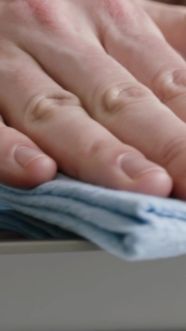Vertical video: Placing blue cloth, hand pressing and sliding across glass top, cleaning surface