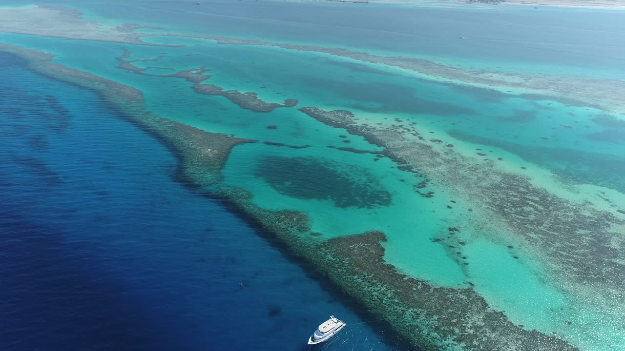 Aerial View of Turquoise Ocean and Coral Reefs with a Yacht