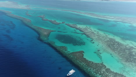aerial view of turquoise ocean and coral reefs with a yacht