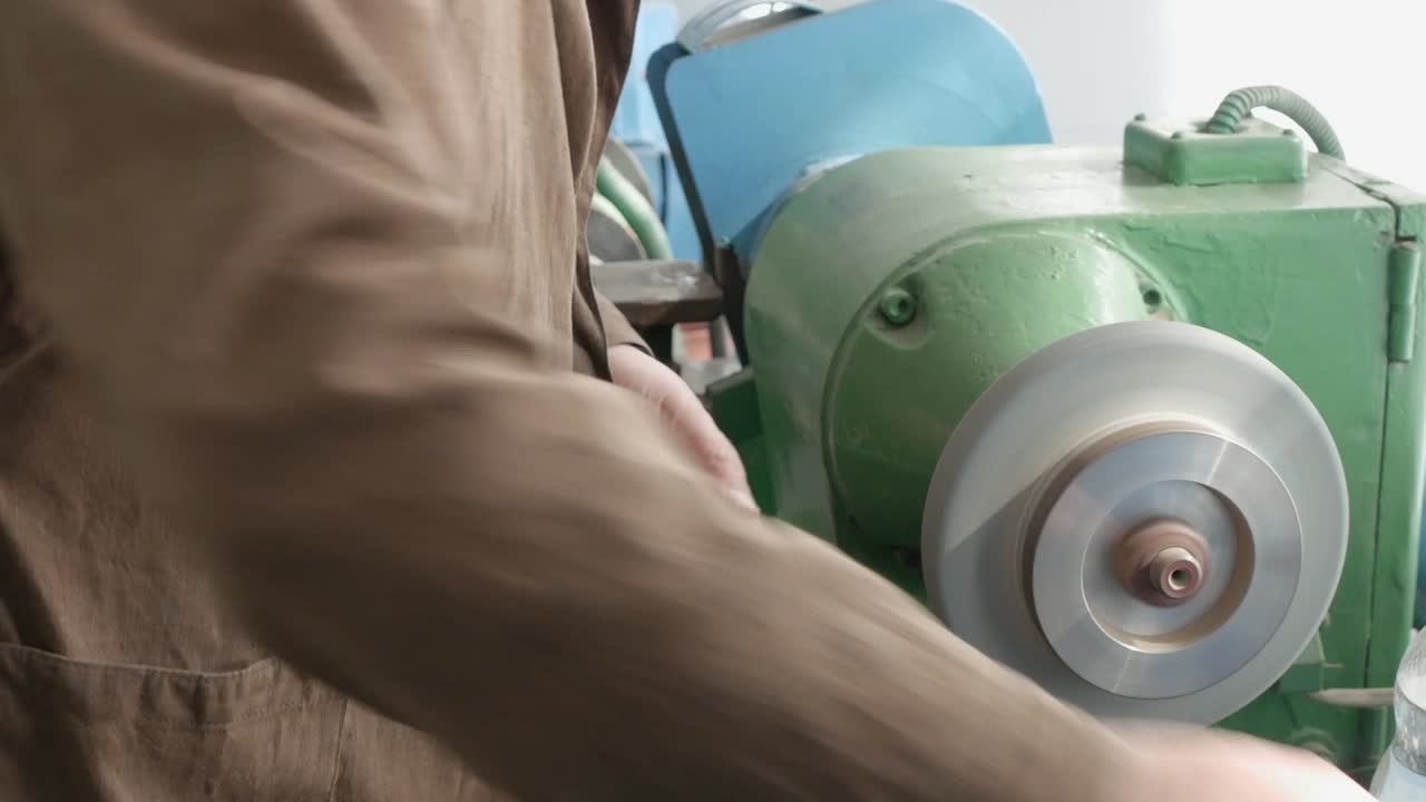 은 손의 마스터는 벤치 그린더, 거친 그린더 머신, 클로즈업, 피데스탈 그린더 작업, 물건 생산, 공장에서 금속 부품을 마무리 는 작업을 수행합니다.