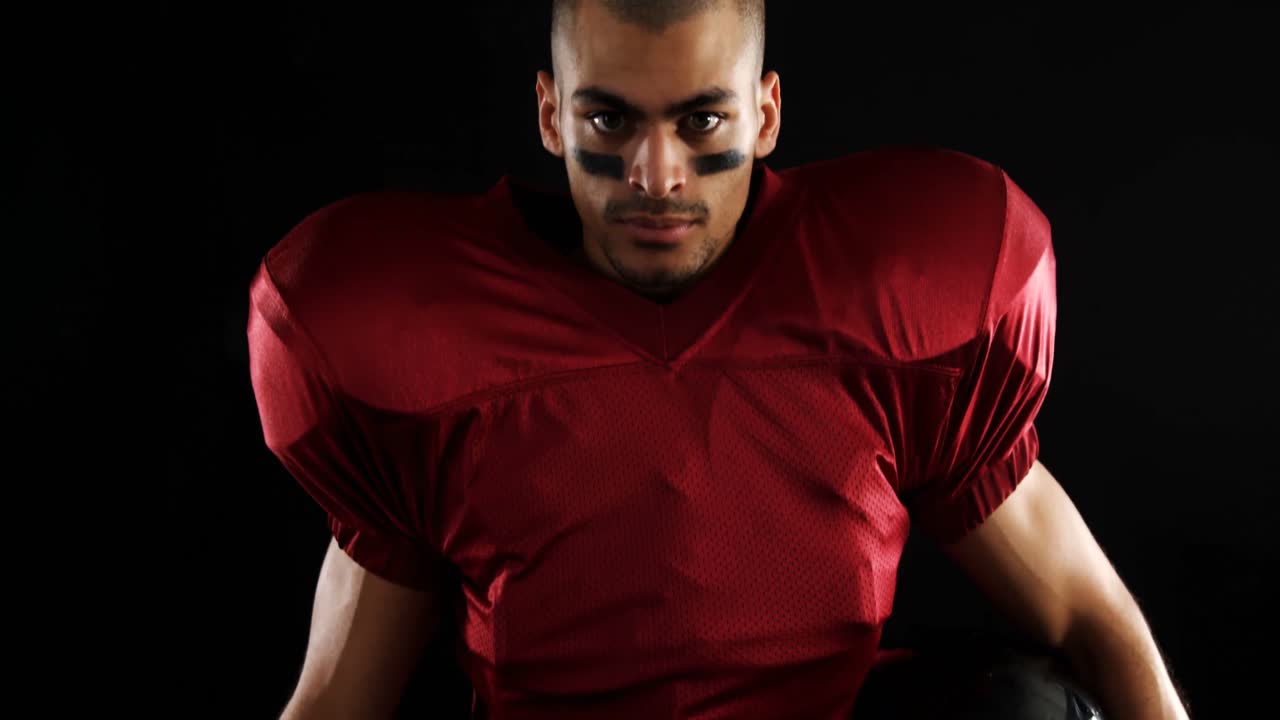 jugador de fútbol americano sosteniendo una pelota y equipo de cabeza 4k