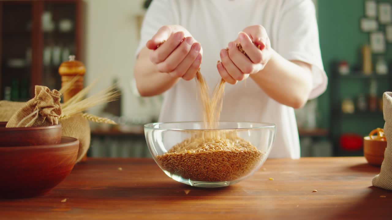 Hands Pouring Flax Seeds into a Glass Bowl