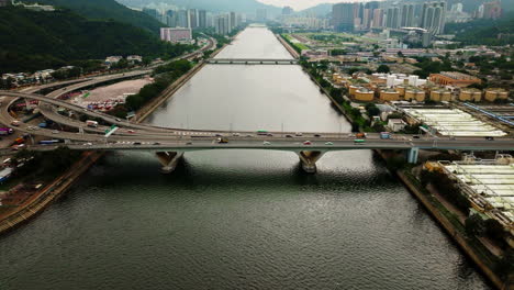 Drone-shot-of-traffic-cars-driving-on-highway-over-a-wide-waterway-bridge,-China