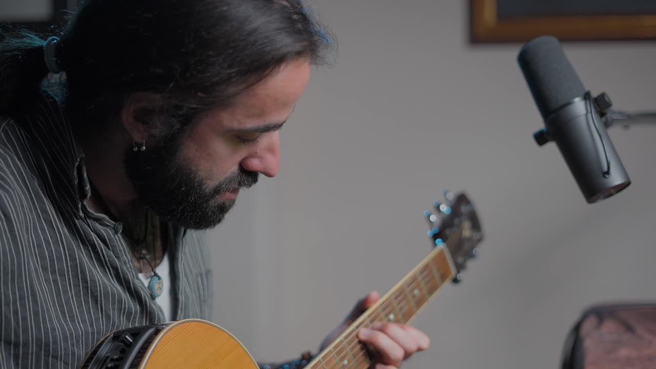hombre tocando la guitarra acústica en el estudio casero