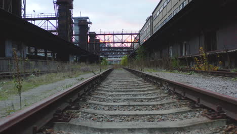 empty weedy railway tracks in an abandoned industrial area at sunset