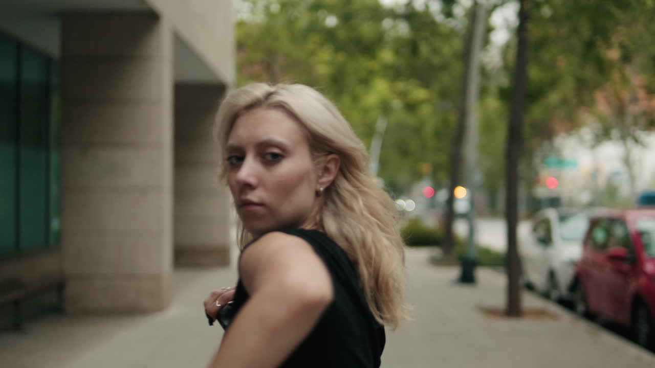 Young Blonde Woman Dancing Expressively on City Sidewalk