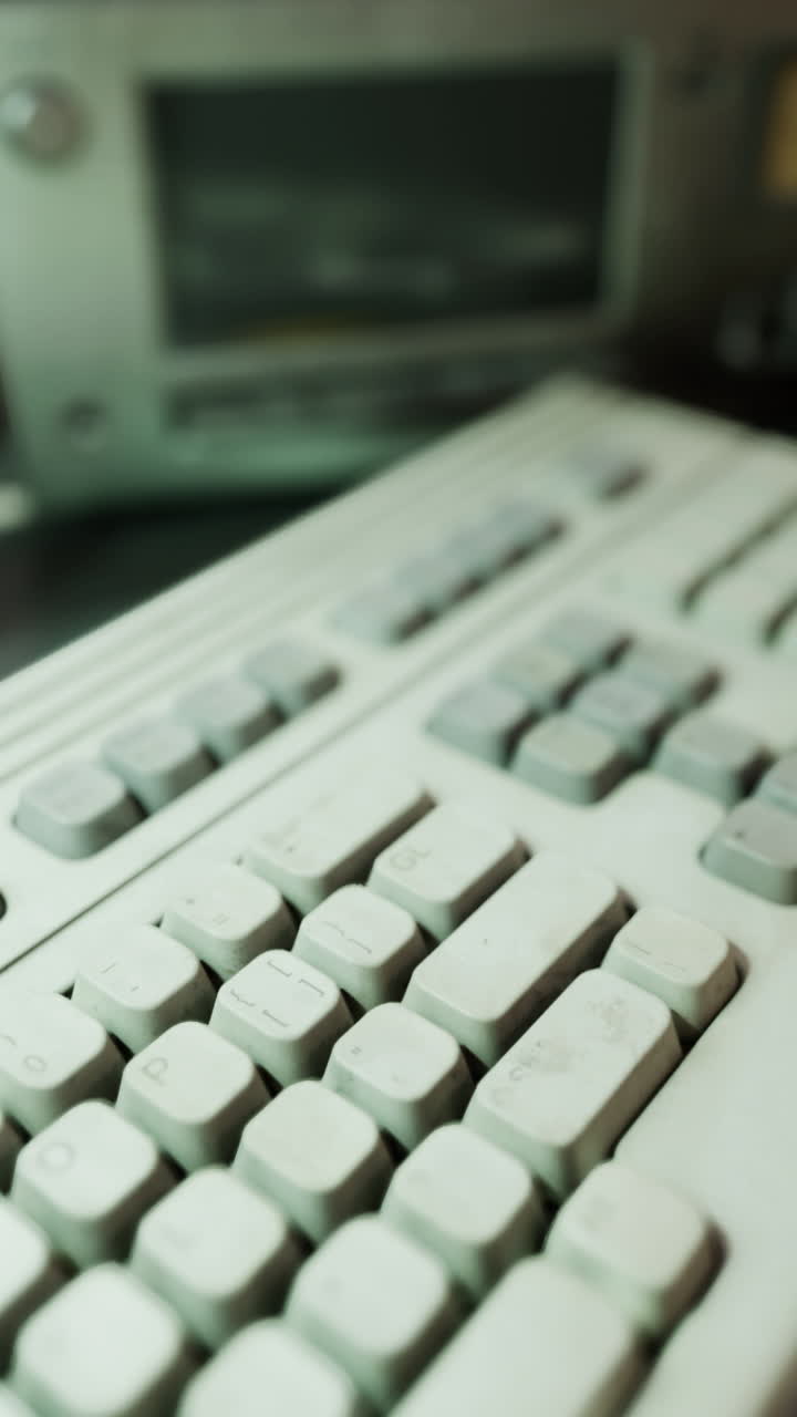 cerca de un viejo teclado blanco con una computadora en el fondo