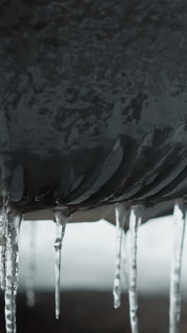 close-up of icy stalactites hanging from a car's mudguard, showcasing frozen textures and the effect of subzero temperatures on vehicle exteriors
