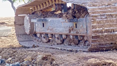 close up of a excavators tracks as it moves across a construction site