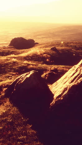 sunset over a grassy field with rocks