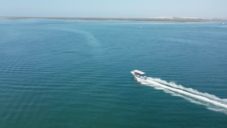 Aerial-tracking-shot-of-speed-fisherboat-driving-on-ocean-for-fishing-during-sunny-day