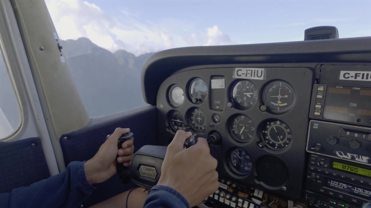 Hands Holding Pilot Yoke Steering Small Cessna Aircraft Dashboard In Flight Past Mountain Ridge. - aerial shot