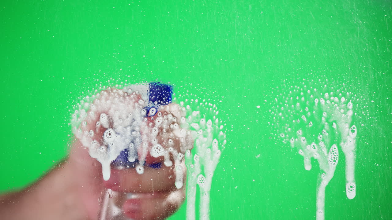 Mano che spruzza schiuma detergente su green screen