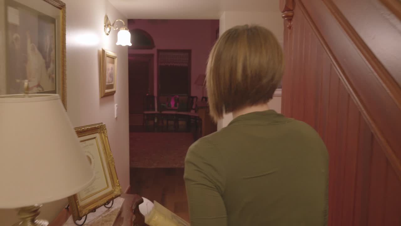 A woman is seen walking down a stair case and turns around to see if someone is there