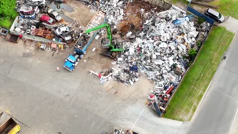 Overhead footage of machinery sorting metal scrap piles in an industrial yard.