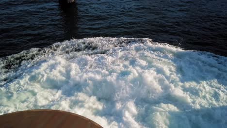 Slow-pan-down-of-ferry-docking-at-Point-Defiance-terminal,-Tacoma-Washington,-prop-wash,-emerald-blue-green-water,-sunset-shadows