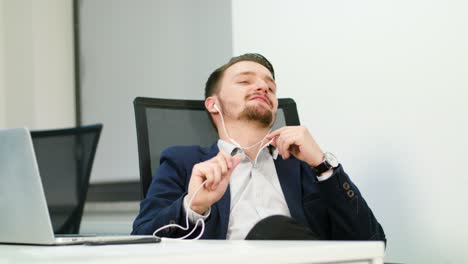 young businessman listening to music in office