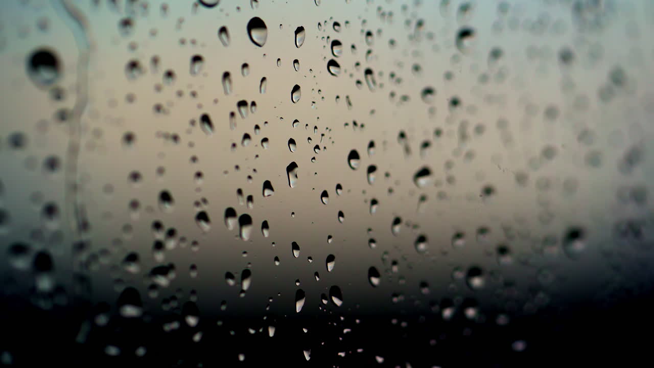 Rain drops on glass. Texture of rain drops on black background. Water droplets on glass. Rain drops on the a window pane after the rain. Close-up.