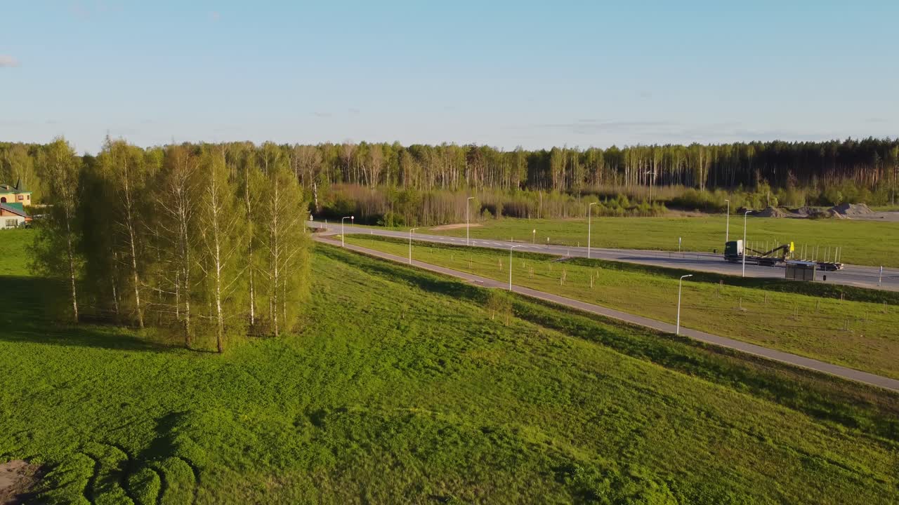 Aerial pedestal view of highway traffic cutting through lush green natural landscape