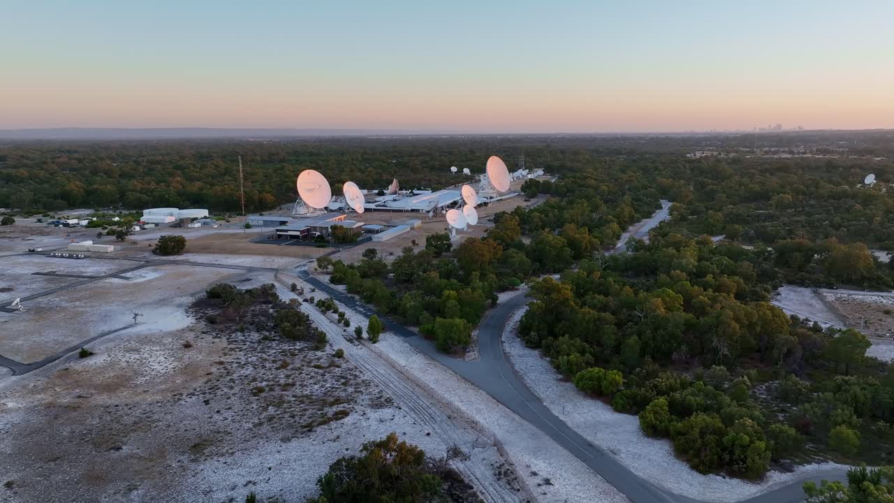 Sunset View Of Satellite Communication Facility With Satellite Dishes Surrounded By Forested Landscape. wide aerial shot