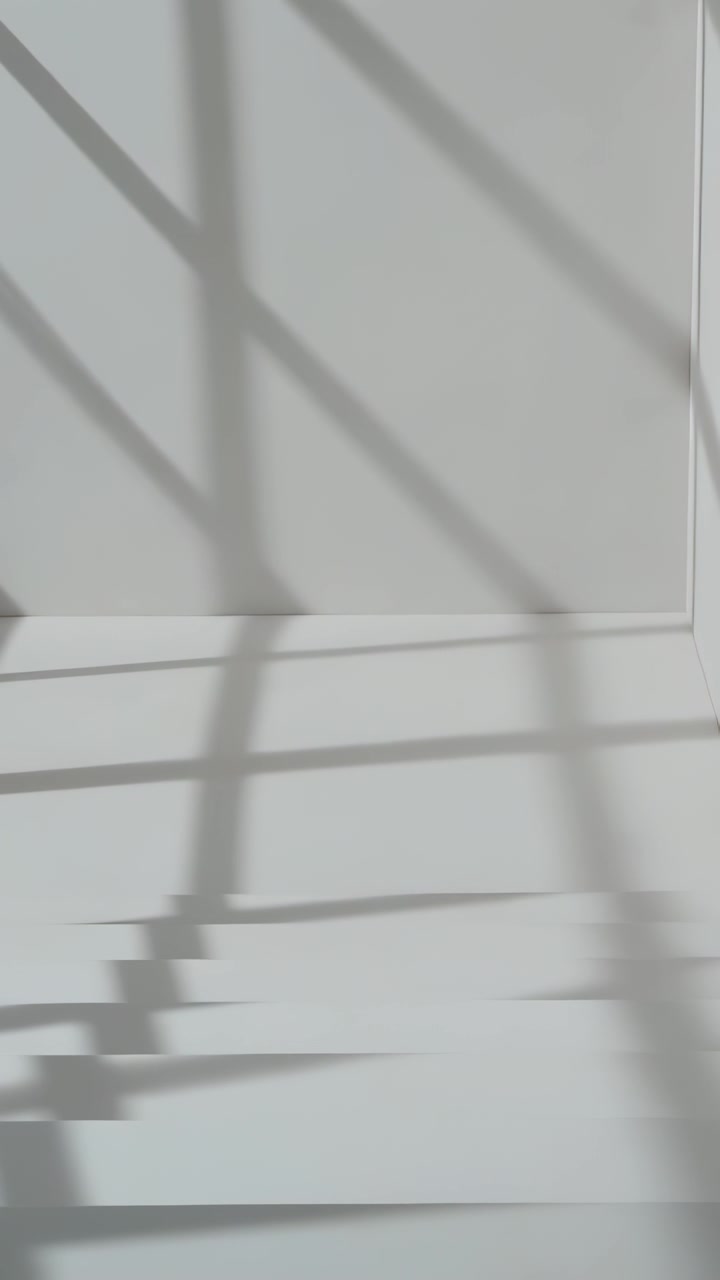 Vertical video: Sun shift moving light through window casting diagonal slat shadows on wall panel