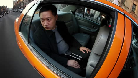 Man riding in the back of a taxi on a city street
