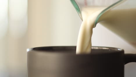 close up pouring milk into mug