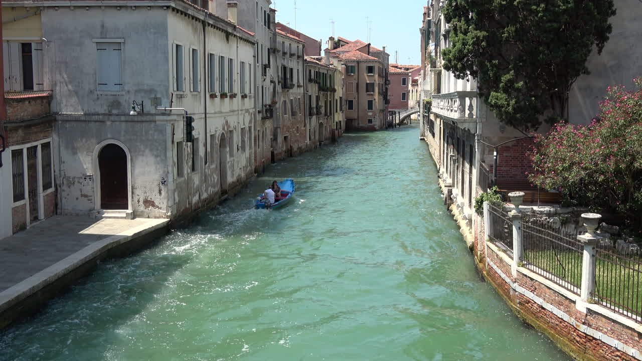 Ampia veduta di un tranquillo canale con acqua turchese che scorre tra vecchi edifici residenziali, architettura veneziana tipica e atmosfera di viaggio a Venezia, Italia.