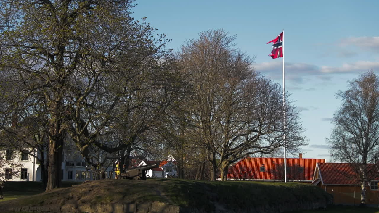 The Norwegian flag on a flagpole being blown by the wind at Fredriksvern verft (Stavern Fort). Stavern, Norway