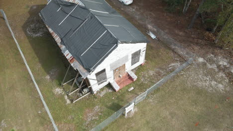 Abandoned-wooden-cabin-boarded-up-within-wilderness-Ascending-aerial