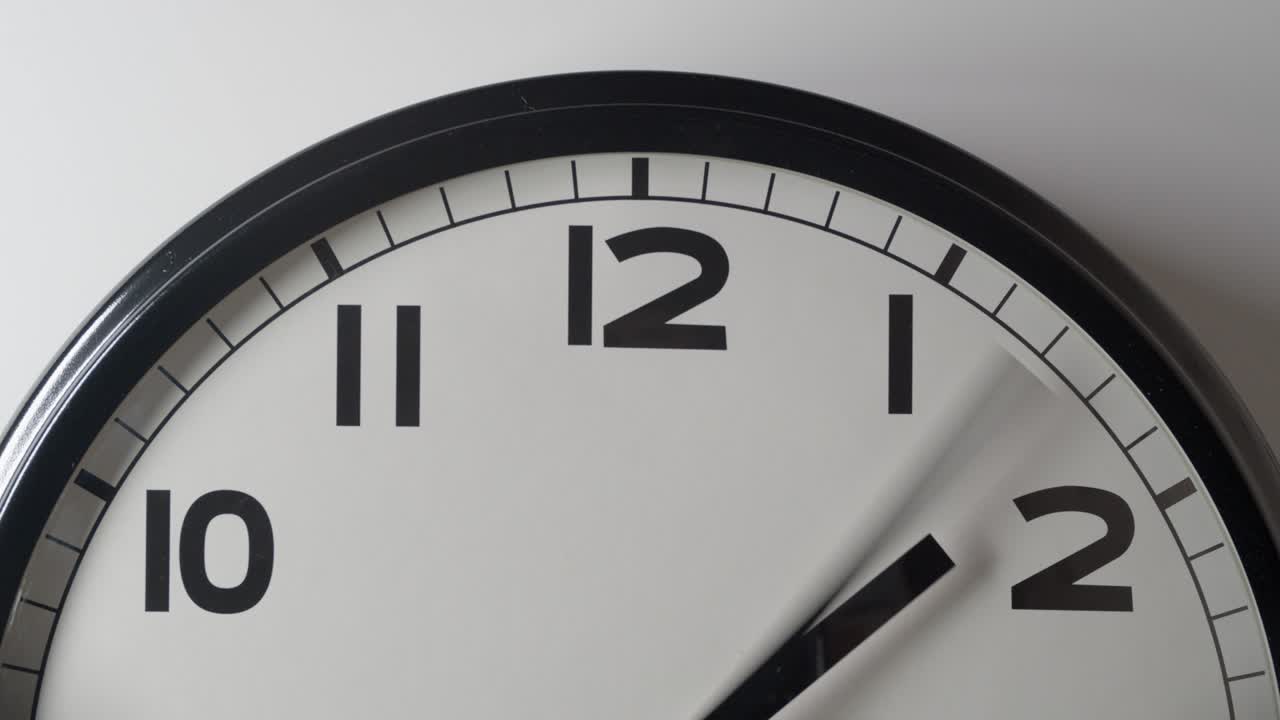 Primo piano del quadrante bianco dell'orologio in time-lapse su parete bianca.