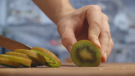 cortar con un cuchillo en una tabla de madera de primer plano kiwi en la cocina. triturar