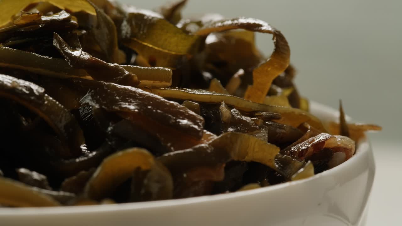 Japanese wakame sea weed laminaria chuka fermented food. Close-up on a detail of Hiyashi Wakame Chuka or seaweed salad or seaweed with sesame seeds on a plate. Top view. Seafood background.