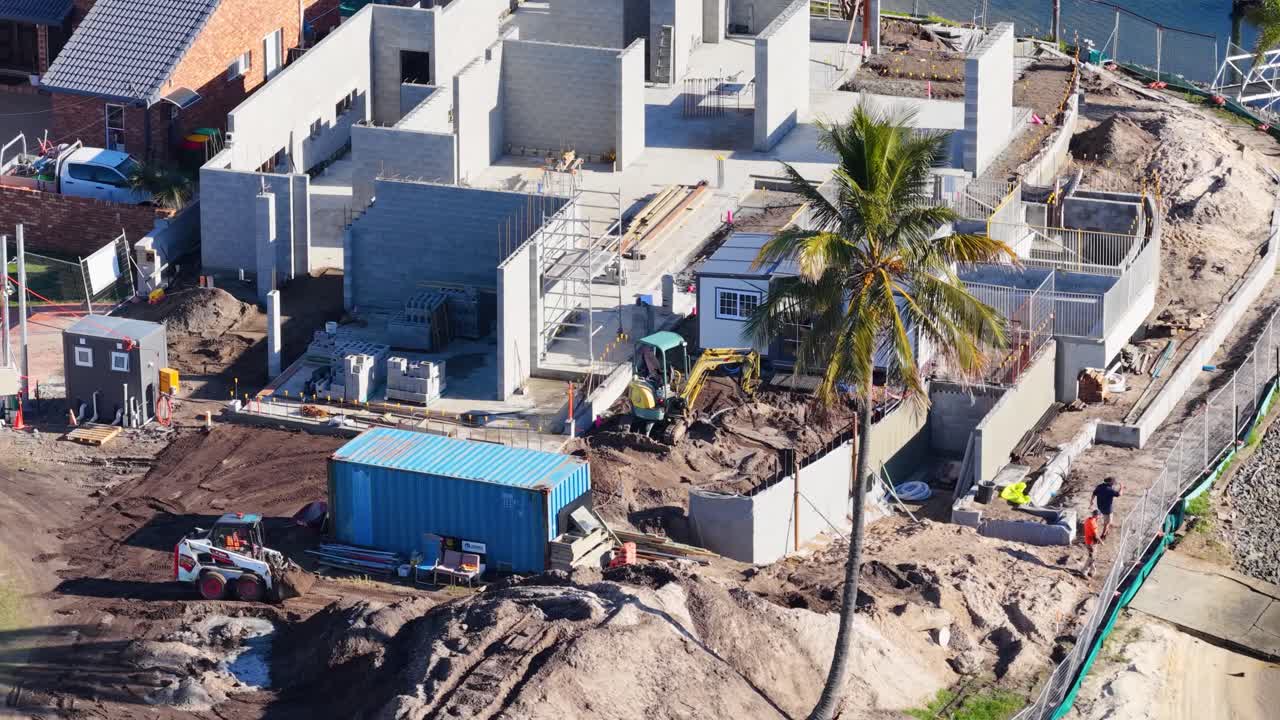 Drone captures construction workers and machinery at a building site in Gold Coast, Australia. Bright daylight enhances visibility
