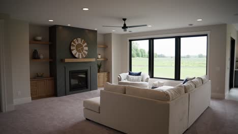 Push-in-wide-shot-of-basement-living-room,-white-couch,-dark-fireplace-mantel,-large-wooden-clock