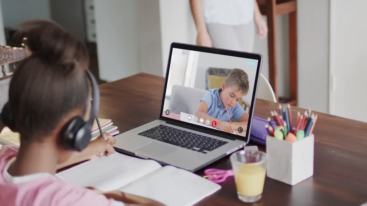 una estudiante diversa teniendo una clase en una llamada de video portátil con su amiga en cámara lenta