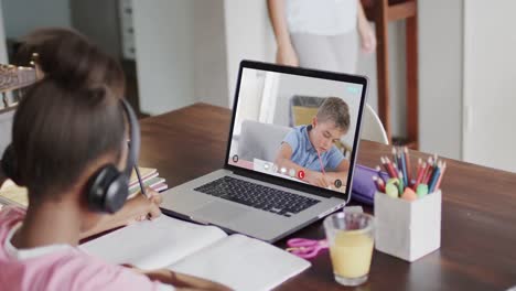 Diverse-schoolgirl-having-class-on-laptop-video-call-with-her-friend-in-slow-motion