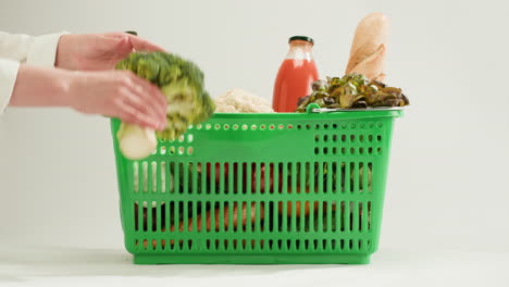 woman shopping with a green basket full of fresh produce