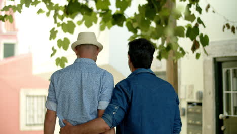 back view of gay man walking with boyfriend and hugging his waist