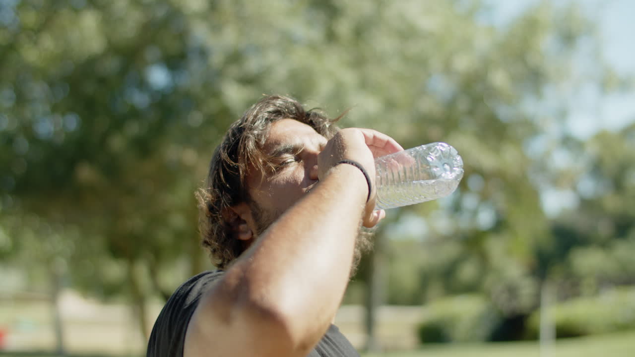 fotografía de cerca de un atleta cansado bebiendo agua durante el entrenamiento