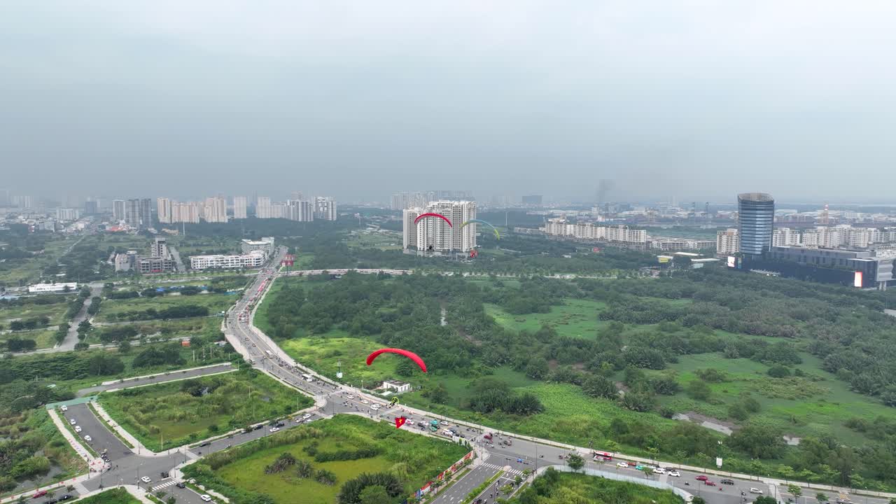 A powered paraglider soaring over green landscapes and cityscape of ho chi minh city, aerial view