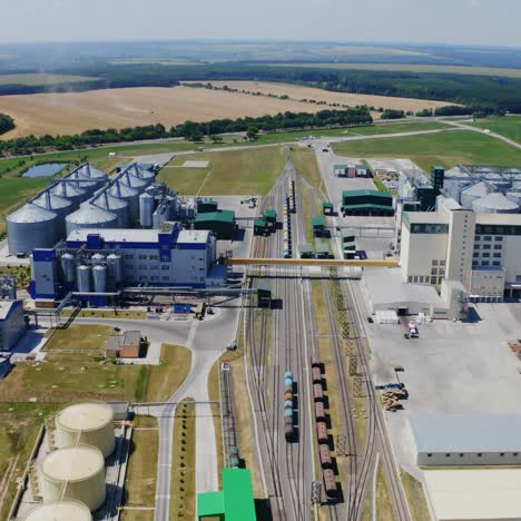 modern plant in farmland. huge territory with large silos and warehouse for keeping agricultural products. factory among beautiful nature. aerial view.